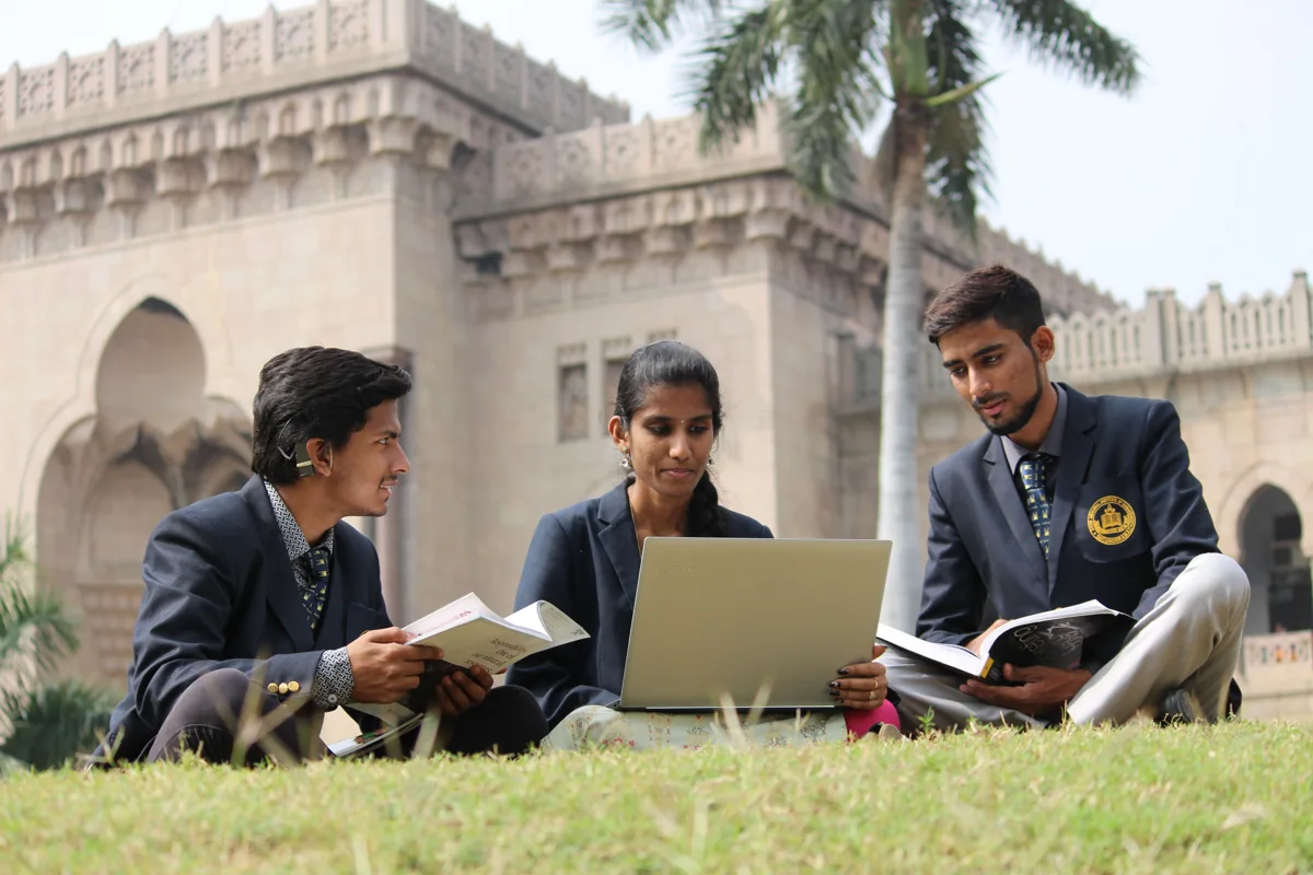 Indian students sharing books and a laptop during group study